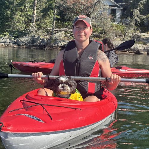 Chris K sits in a kayak with her dog.